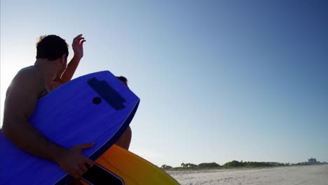 Multi-ethnic-people-jogging-with-bodyboards-on-beach