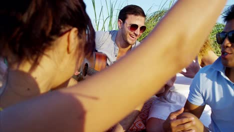 Multi-ethnic-people-enjoying-beach-party-with-guitar