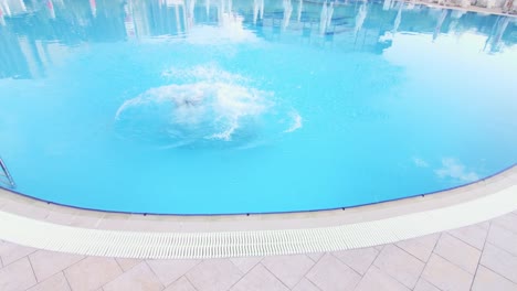 Two-girls-jump-in-swimming-pool-wide-shot