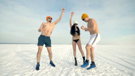 Dos-hombres-y-una-mujer-en-bikini-bailan-sobre-la-nieve.-4K.