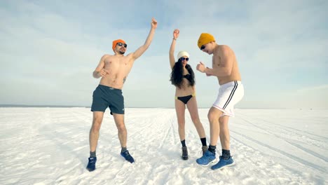 Zwei-Männer-und-eine-Frau-im-Bikini-tanzen-auf-dem-Schnee.-4K.