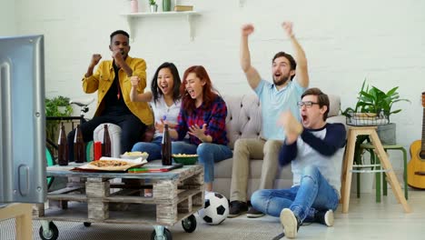 Grupo-de-amigos-felices-viendo-el-juego-de-deportes-en-la-televisión-en-casa.-Ellos-están-contentos-con-su-competencia-de-victoria-del-equipo-favorito