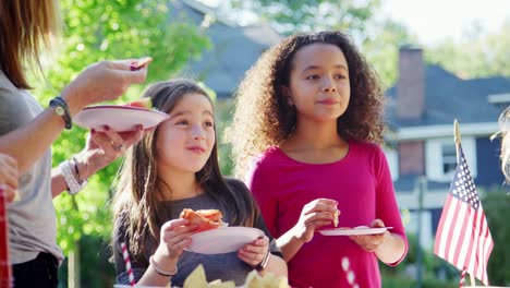 Mädchen-stehen-Essen-Pizza-mit-Nachbarn-auf-einen-Block-party