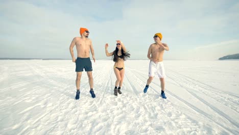 Tres-amigos-bailan-y-saltan-durante-la-formación-frio-mientras-usa-trajes-de-baño.-4K.