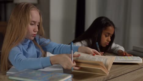 Two-diverse-teeanage-girls-doing-homework-at-home