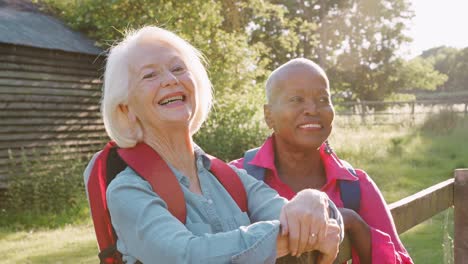 Portrait-Of-Two-Female-Senior-Friends-Hiking-In-Countryside