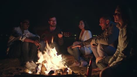 Gruppe-von-Freunden-singen-am-Lagerfeuer