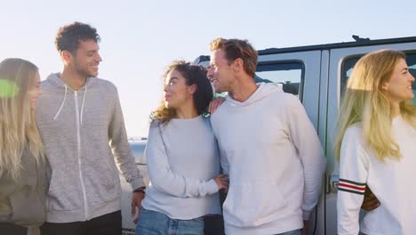 Young-adult-friends-on-a-road-trip-standing-by-car-talking