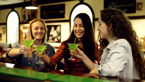 Best-friends-are-toasting,-clanging-glasses-and-drinking-cocktails-in-fancy-bar.-Women-are-celebrating-something-together.