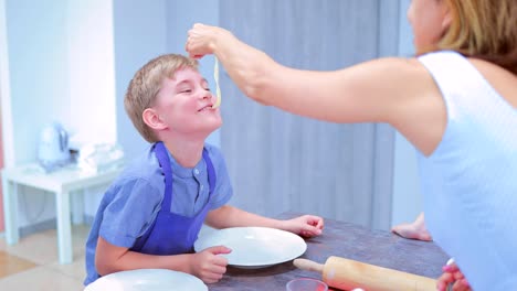 Kulinarischen-Frau-gibt-einen-kleinen-Jungen-in-der-Küche,-eine-Pasta-zu-probieren