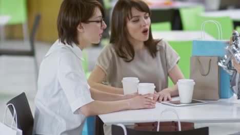 Mujer-mostrando-las-compras-a-los-amigos-en-el-café