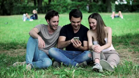 Gruppe-von-Freunden-im-Park,-lachen,-Blick-auf-das-smartphone