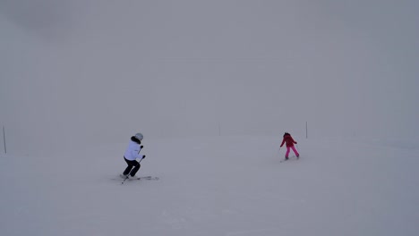 Dos-esquiadoras-de-esquí-en-el-descenso-de-montaña-en-invierno-en-niebla-pesada