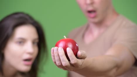 Young-couple-looking-surprised-at-apple-together