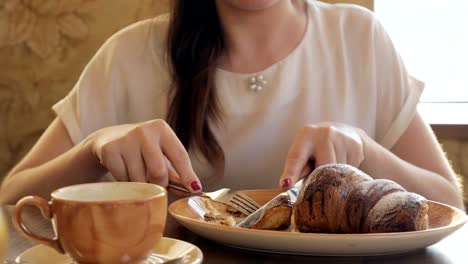 Brünette-Frau-Essen-ein-Croissant-und-Gesang-Kaffee-in-einem-café