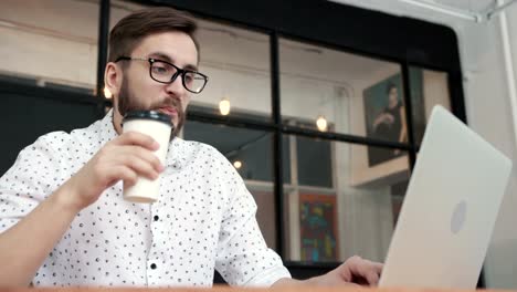 Man-working-in-office-at-laptop-and-drink-coffee