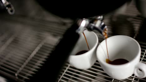 Super-slow-motion-of-hot-espresso-coffee-pouring-into-a-two-white-porcelain-cups-from-coffee-machine-in-4k-(-top-view-close-up)