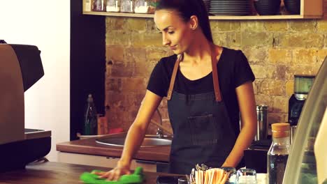 The-owner-of-a-coffee-house-wipes-a-wooden-table.