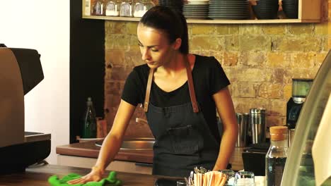 The-owner-of-a-coffee-house-wipes-a-wooden-table.