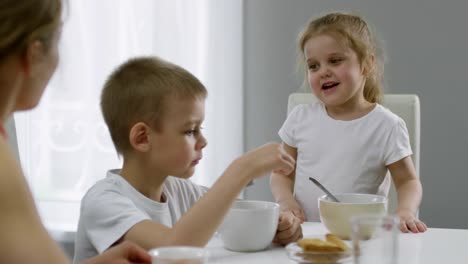 Süße-Mädchen-im-Chat-mit-Mutter-und-Bruder-beim-Frühstück