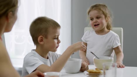 Chica-linda-chateando-con-madre-y-hermano-en-el-desayuno