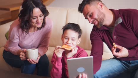 Familia-feliz-con-tableta-digital-mientras-pizza-en-sala-de-estar