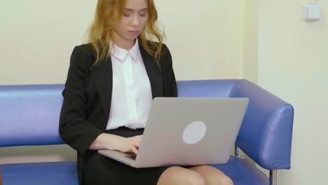 Business-woman-using-notebook-pc-for-work-sitting-on-sofa-in-business-office