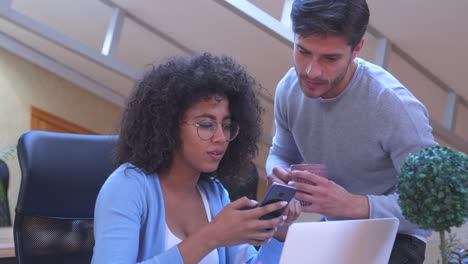 Mann-und-Frau-Teilen-von-Medieninhalten-auf-Handy-im-Büro