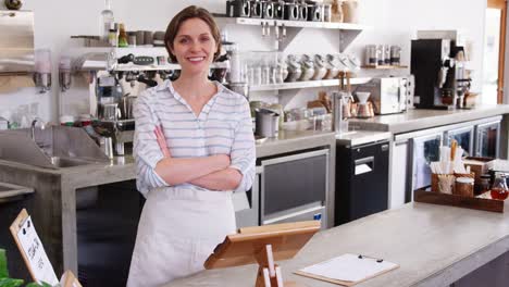 Weibliche-Coffee-Shop-Besitzer-stützte-sich-auf-Zähler-im-Coffee-shop