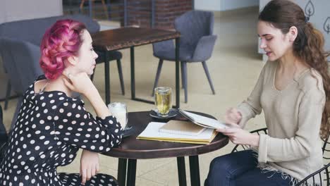 Woman-drawing-sketch-and-talking-with-friend-at-cafe