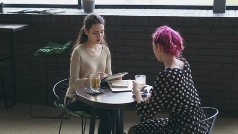 Woman-drawing-sketch-and-talking-with-friend-at-cafe