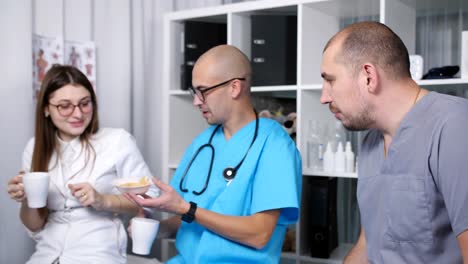 Three-doctors-in-the-staffroom-talk-and-drink-coffee-at-the-break.