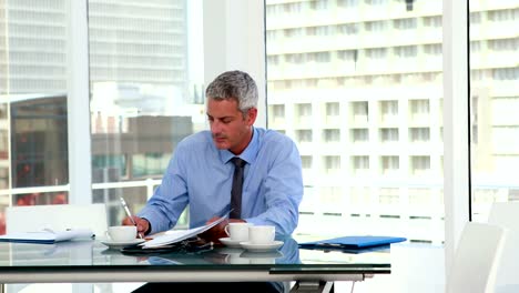 Serious-businessman-writing-on-notebook