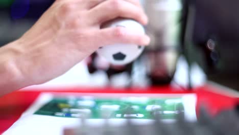 Male-hand-plays-with-mini-football-toy-on-table