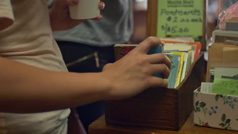 Close-up-of-somebody-looking-through-a-box-of-antique-postcards