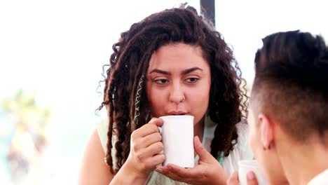 Smiling-lesbian-couple-drinking-coffee-together