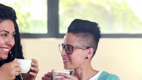 Smiling-lesbian-couple-drinking-coffee-together