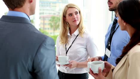 Business-people-standing-at-conference-drinking-coffee