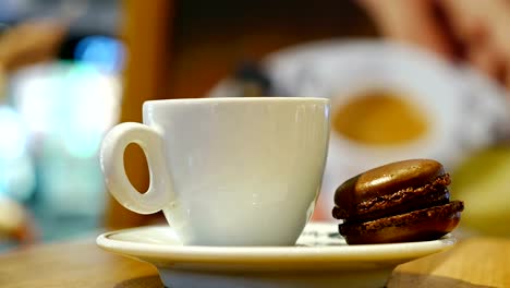 Cup-of-coffee-with-brown-macaron-in-an-indoor-café