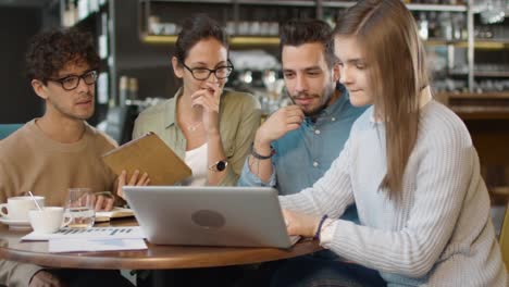 Pequeño-equipo-creativo-de-jóvenes-activos-que-tienen-reunión-y-discusión-en-la-cafetería.