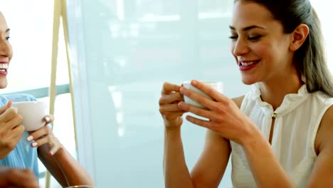 Ejecutivo-sonriente-interactuando-al-mismo-tiempo-que-una-taza-de-café