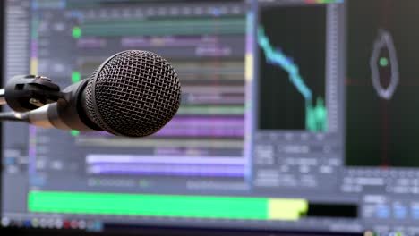 Microphone-on-the-background-of-the-computer-monitor.-Home-recording-Studio.-Close-up.-The-focus-in-the-foreground.-Blurred-background.-Software-for-recording-and-editing-sounds.-4K,-UHD,-Ultra-HD