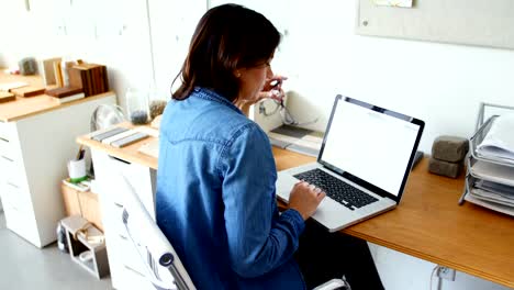 Female-executive-sitting-at-desk-and-using-laptop