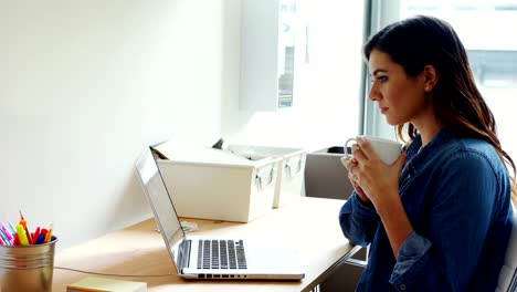 Female-executive-using-laptop-white-having-coffee