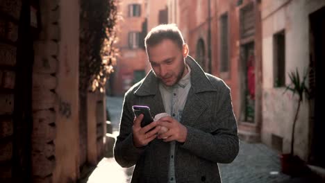 Attraktive-junge-Mann-zu-Fuß-in-die-Stadt-und-mit-Smartphone.-Männliche-mit-Freunden-plaudern-und-Kaffee-trinken