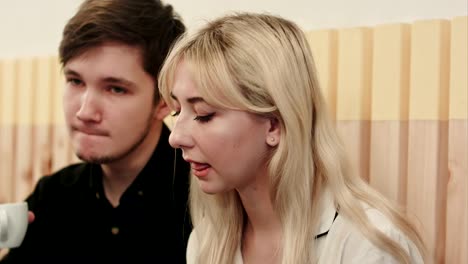 Portrait-of-young-couple-talking-seriously-and-drinking-coffee-at-a-coffee-shop