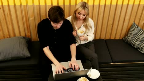 Hipster-couple-sitting-incafe-drinking-coffee-using-laptop