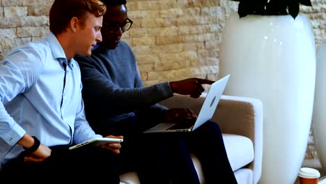 Führungskräfte-diskutieren-über-Laptop-im-Büro