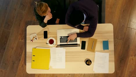 Gerente-y-su-colega-bastante-joven-sentado-en-la-oficina-y-trabajar-en-la-presentación-del-negocio