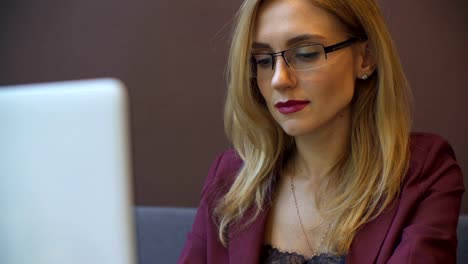 Young-attractive-businesswoman-working-on-modern-laptop-in-cafe